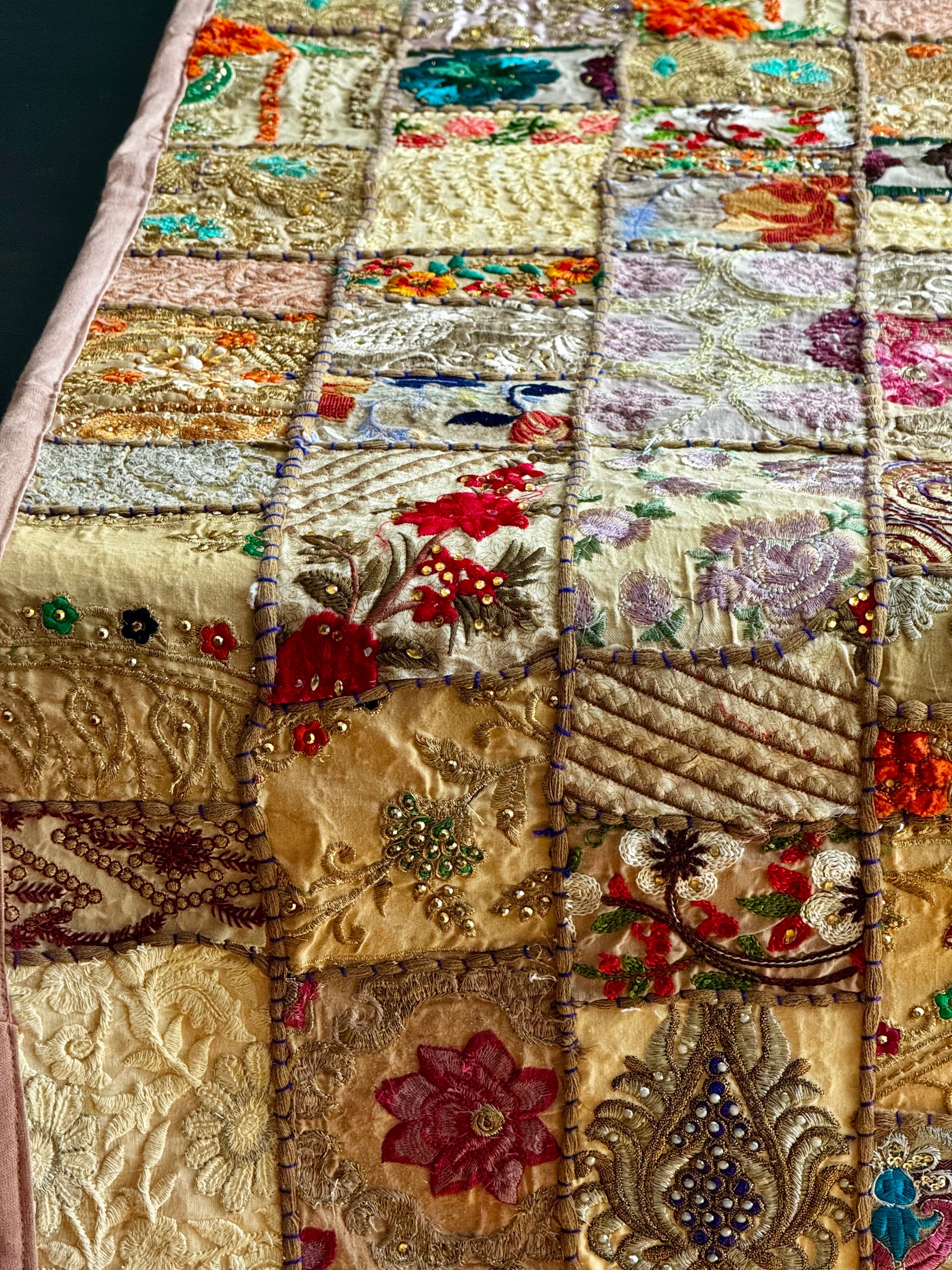 Embroidered Khambhadia patchwork runner closeup with floral patterns and beadwork on a beige background