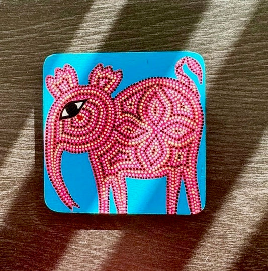 Decorative coaster with a pink and blue design on a wooden surface