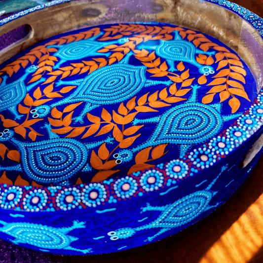 Decorative plate with Bhil art blue and orange patterns on a wooden surface