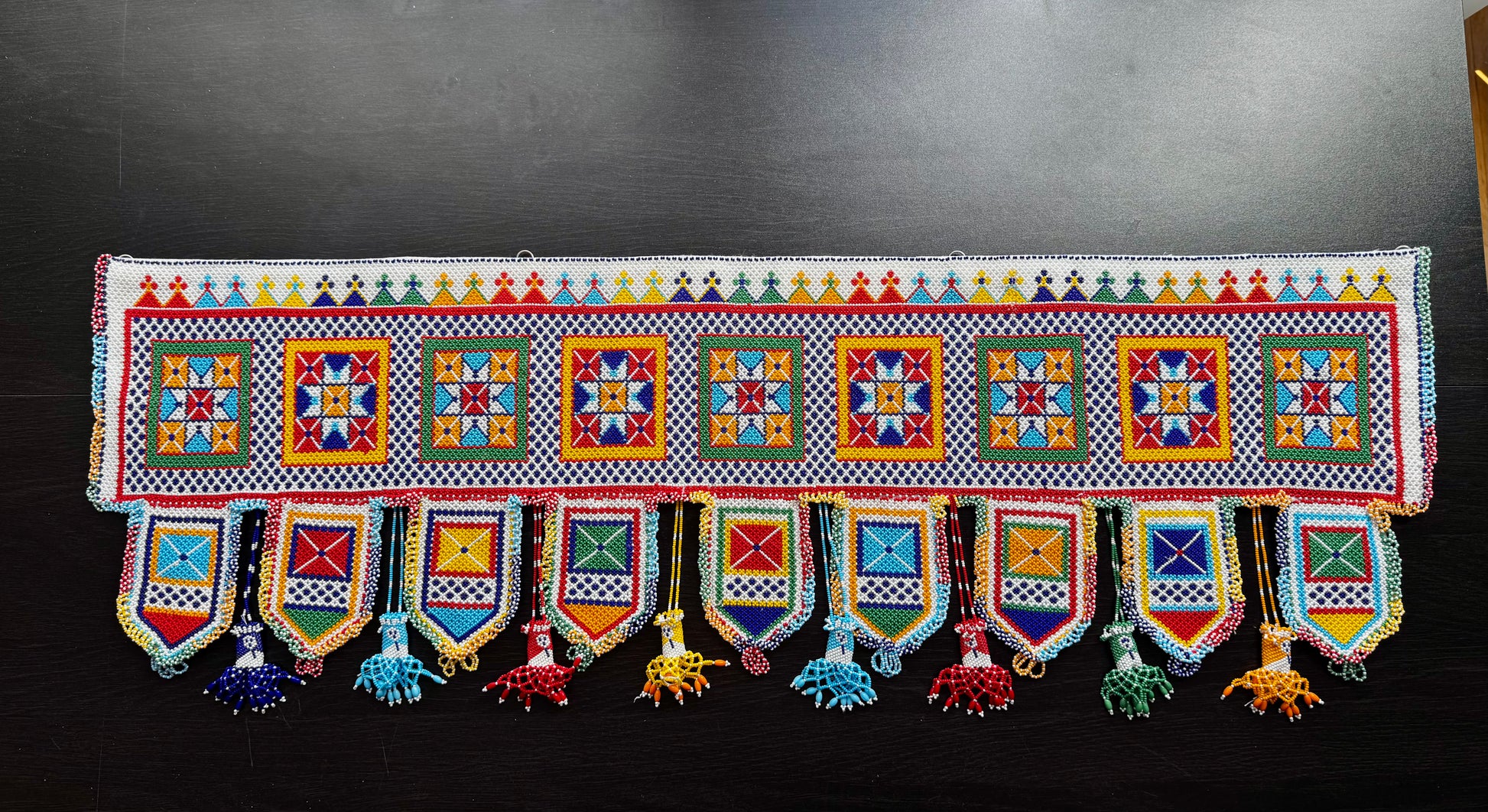 Colorful Motikaam strung pearls art wall/doorway hanging with geometric patterns on a black background