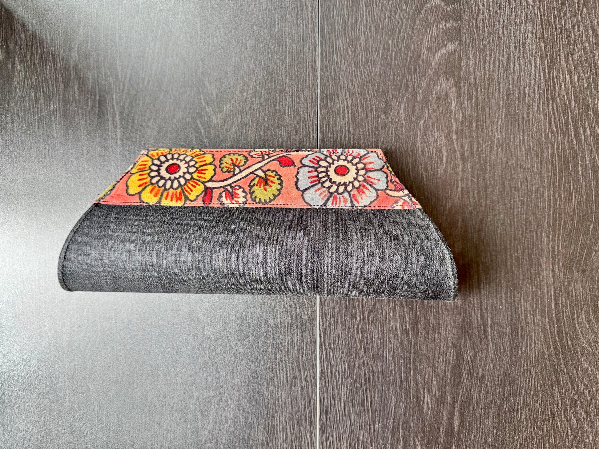 A collection of hand-painted kalamkari clutch purses in various colors, featuring intricate patterns.