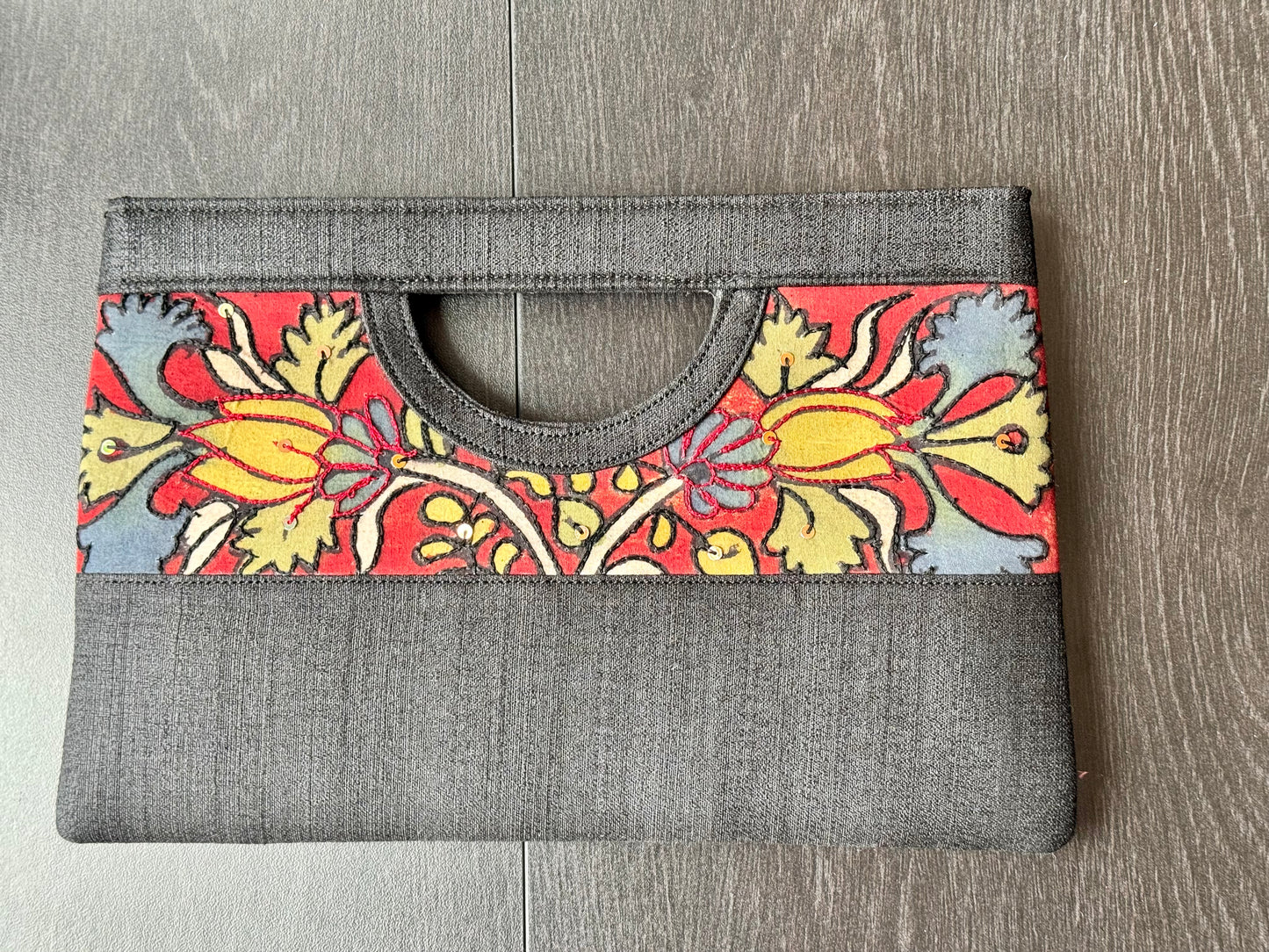 A collection of hand-painted kalamkari clutch purses in various colors, featuring intricate patterns.