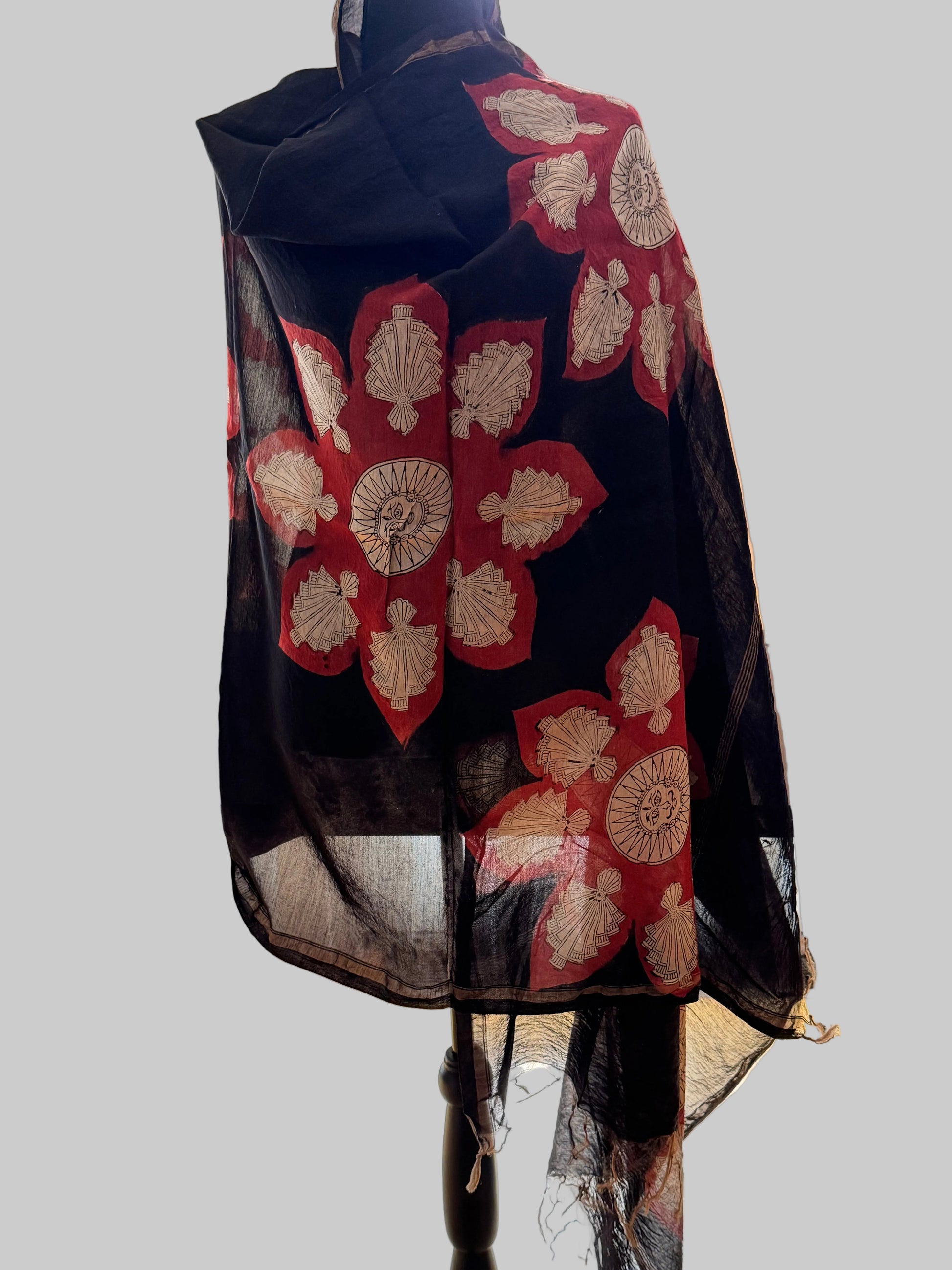 Black stole with red and gold floral patterns hand painted in Mata ni Pachhedi style art on a mannequin against a neutral background