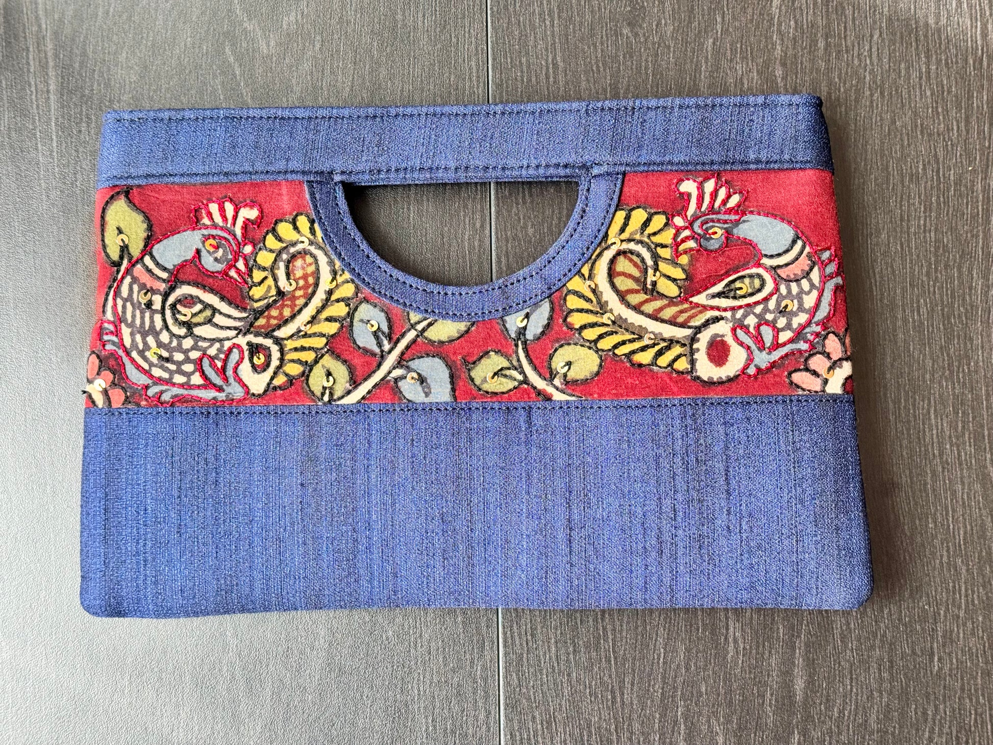A collection of hand-painted kalamkari clutch purses in various colors, featuring intricate patterns.