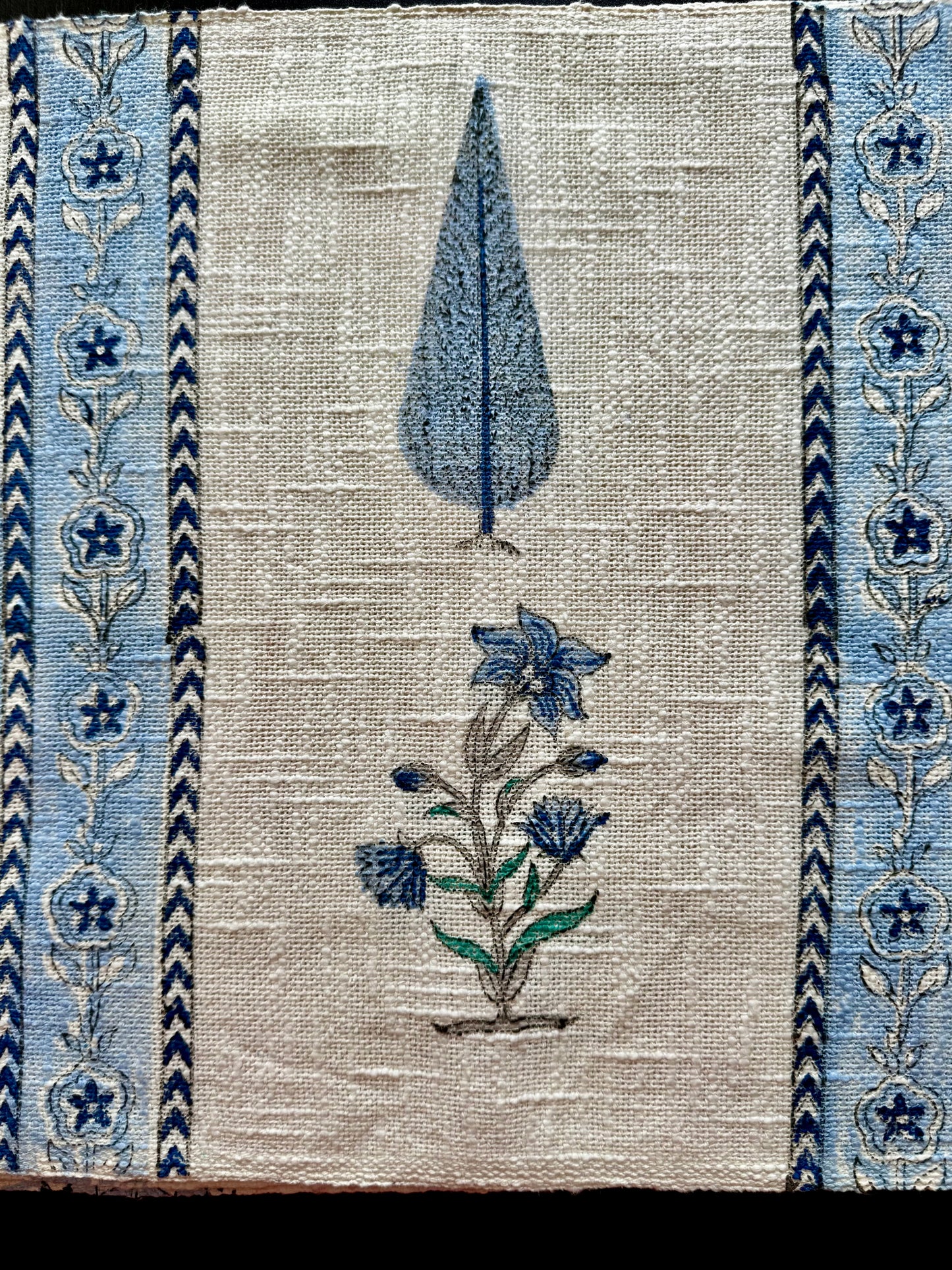 Hand block printed design of a tree and flowers on a textured fabric background with blue floral patterns placemats