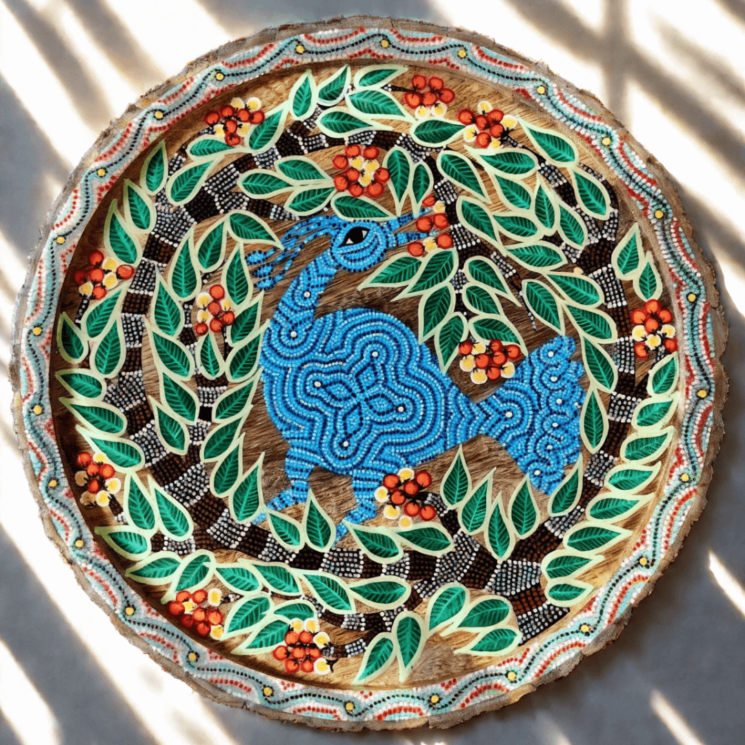 Decorative Bhil art plate with a blue deer surrounded by green leaves and red berries on a white background