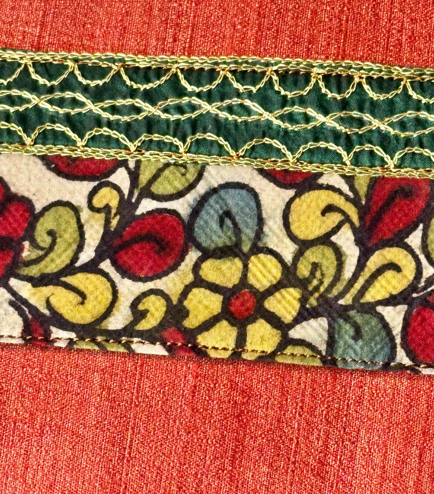 Close-up of a floral patterned fabric with green and gold trim on a red background