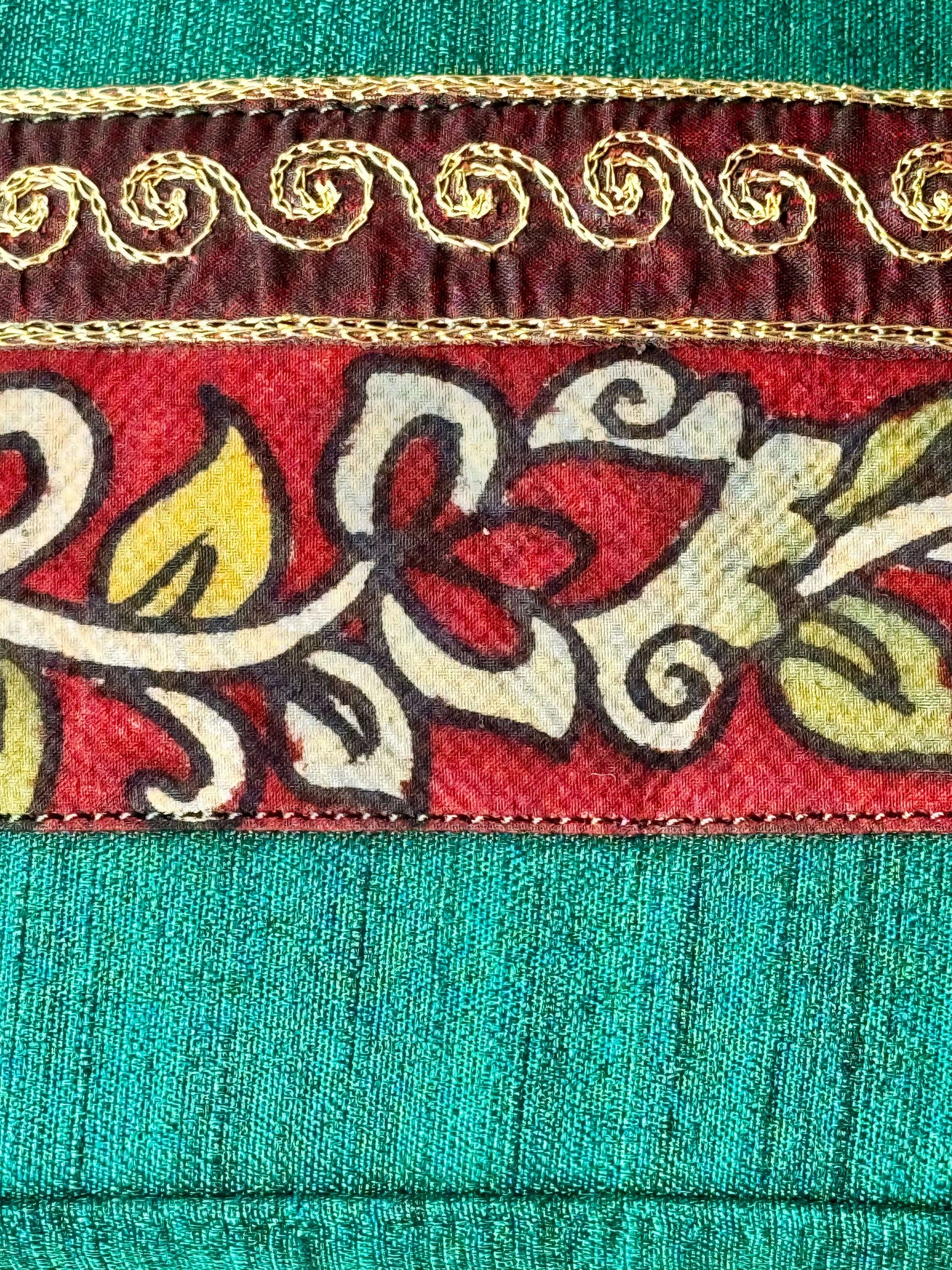 Close-up of hand painted Kalamkari  fabric with intricate patterns on a teal background