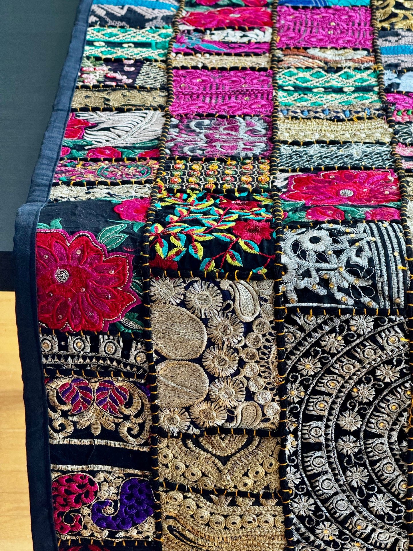 Colorful embroidered Khambhadia patchwork runner with various patterns on a wooden surface
