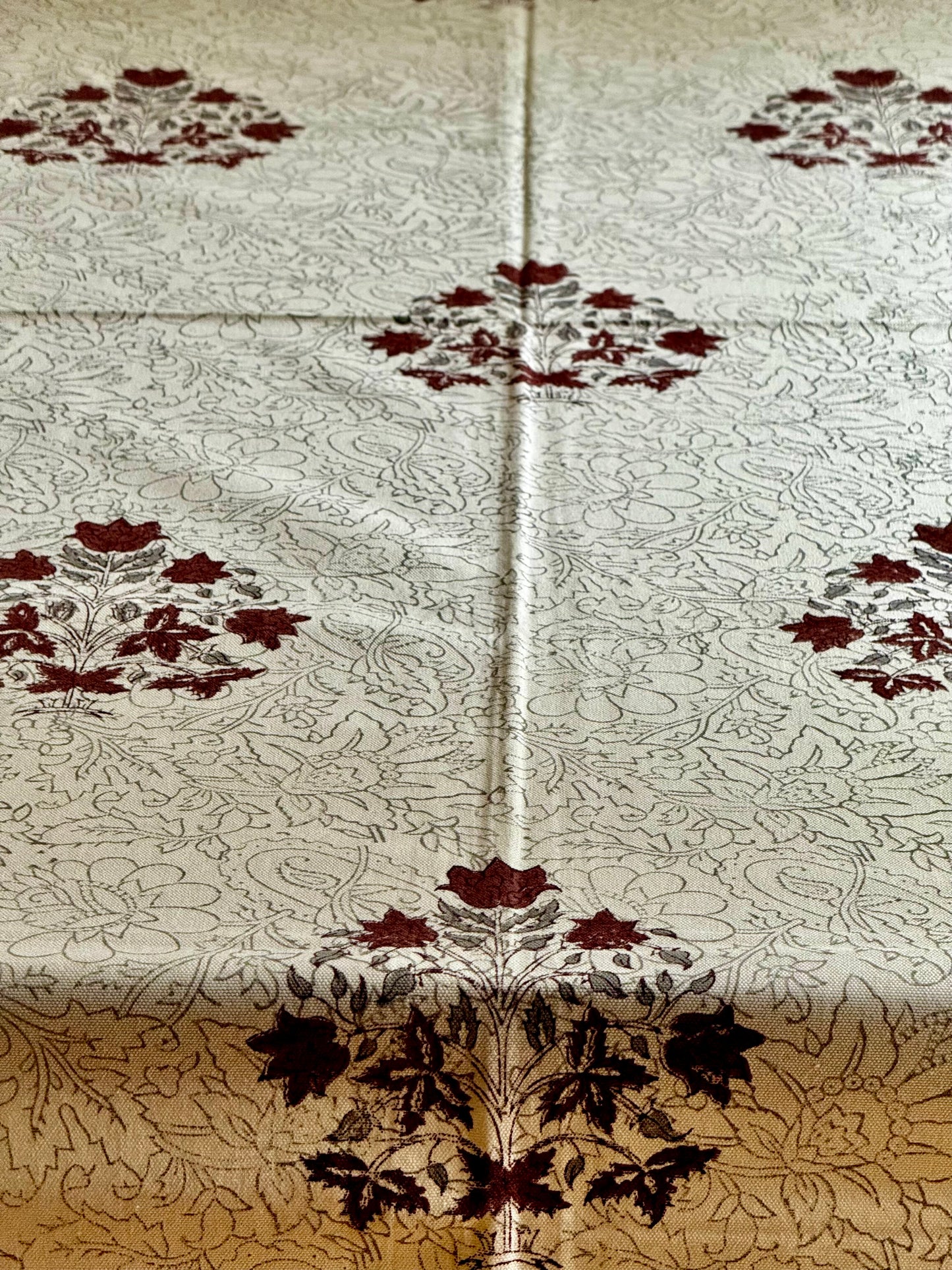 Floral patterned hand block print table cloth close up with a visible fold on a beige background