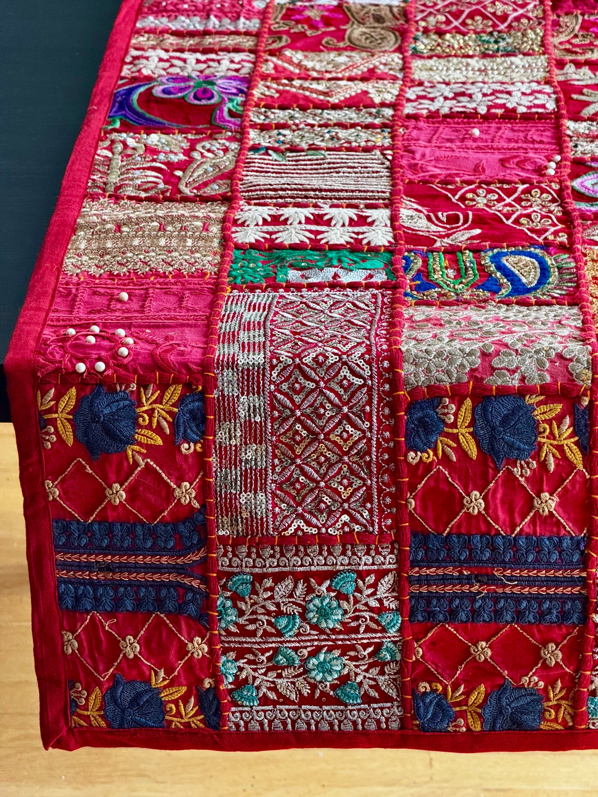 Embroidered red Khambhadia patchwork runner closeup with colorful patterns on a wooden surface