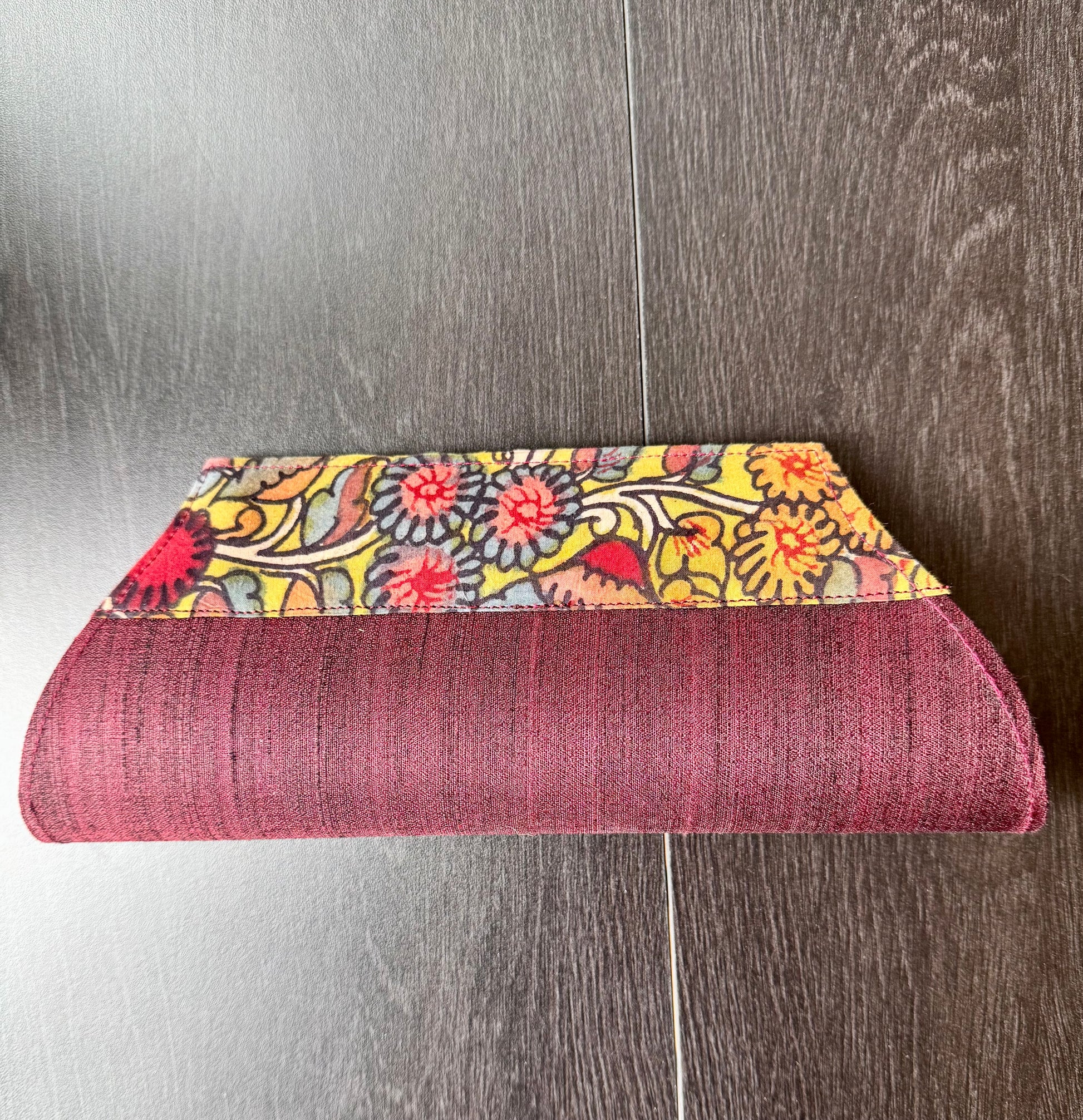 A collection of hand-painted kalamkari clutch purses in various colors, featuring intricate patterns.