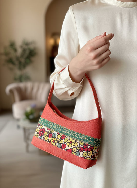 Handbag with floral patterned hand painted Kalamkari strap on a wooden surface