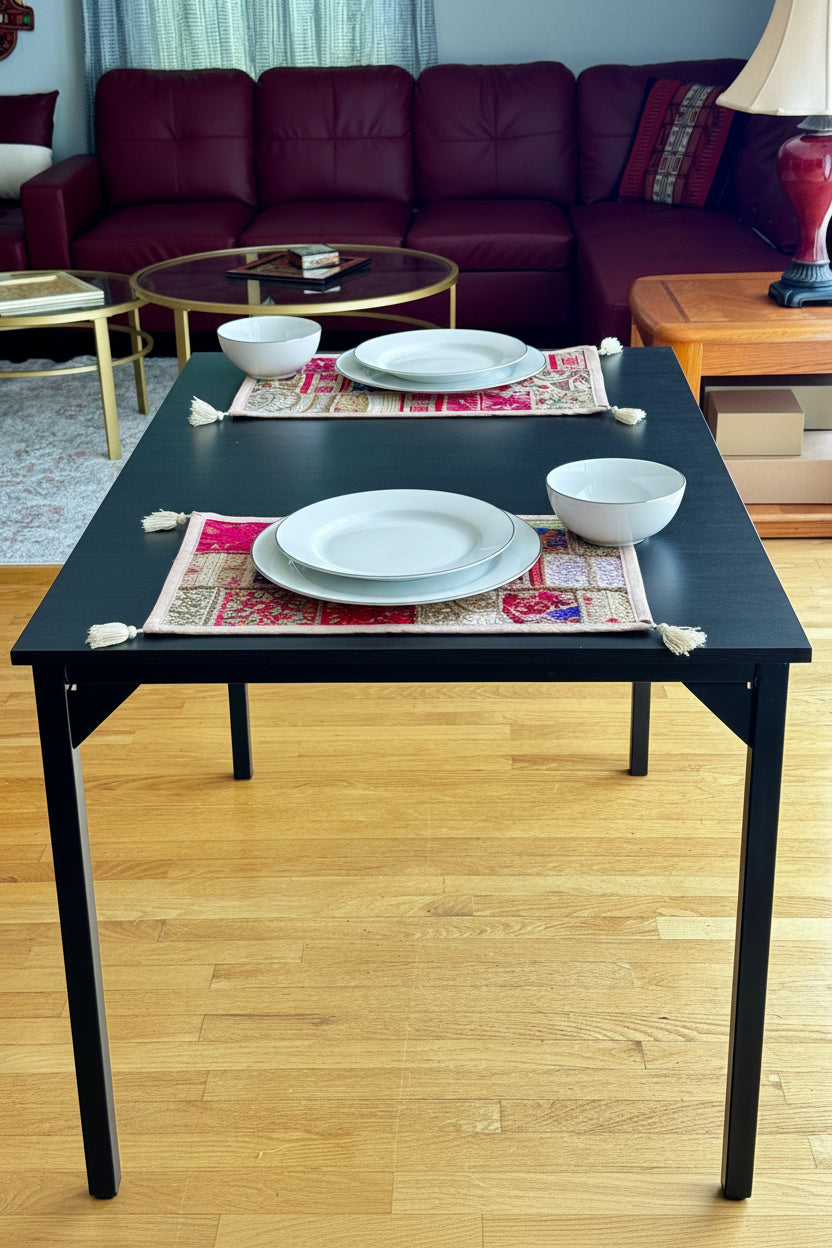 Black table with colorful Khambhadia patchwork placemats in a living room setting