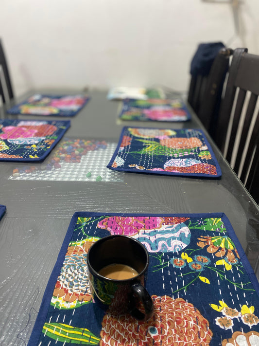 Colorful blue Kantha work placemats on a table with a cup of coffee
