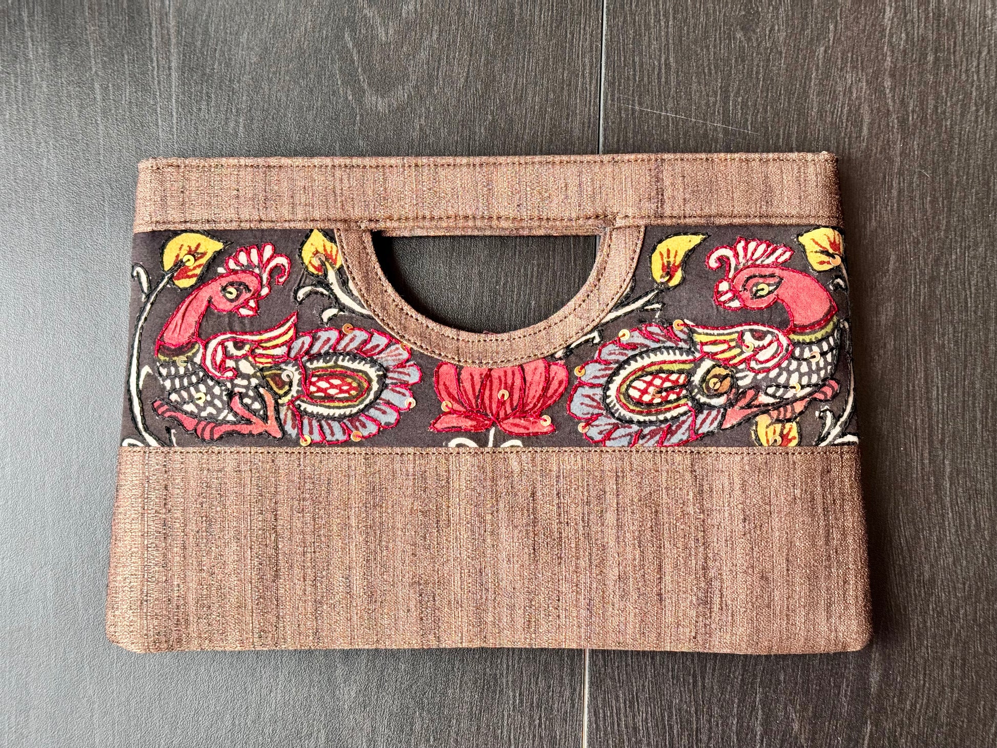 A collection of hand-painted kalamkari clutch purses in various colors, featuring intricate patterns.