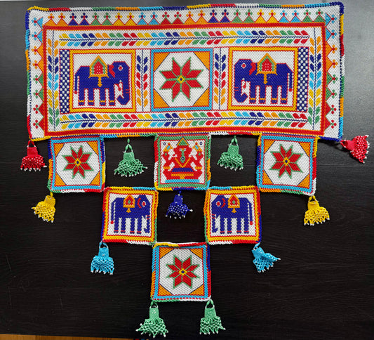 Colorful Motikaam wall hanging with patterns and tassels on a dark background