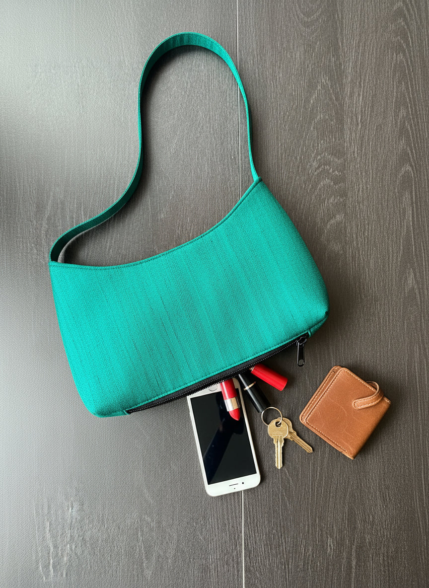 Green handbag with a zipper on a wooden surface