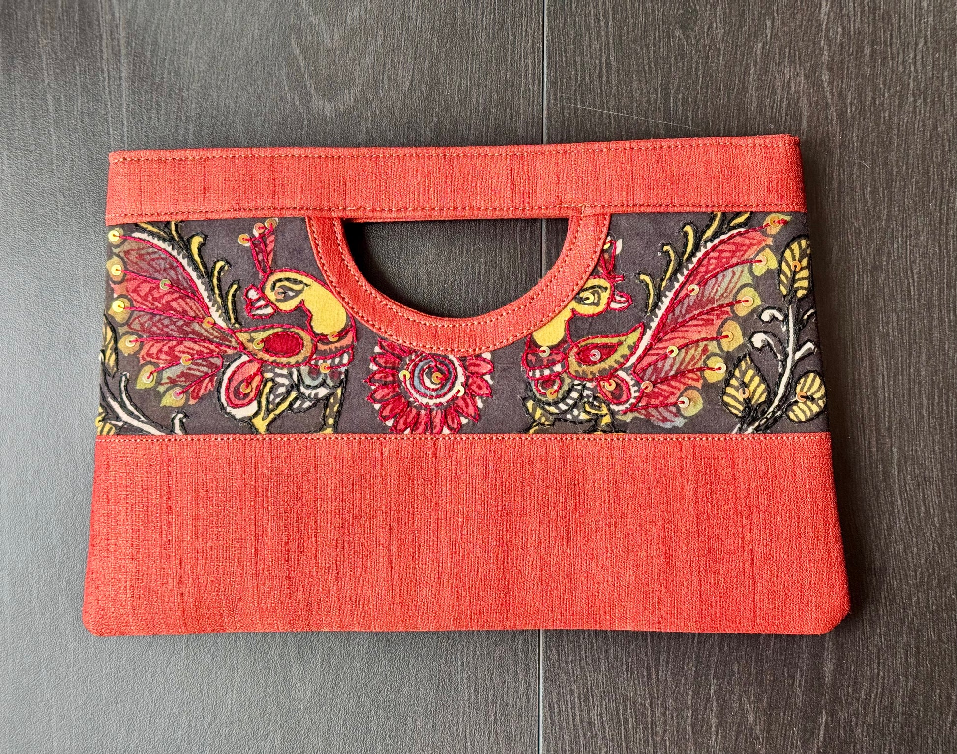 A collection of hand-painted kalamkari clutch purses in various colors, featuring intricate patterns.