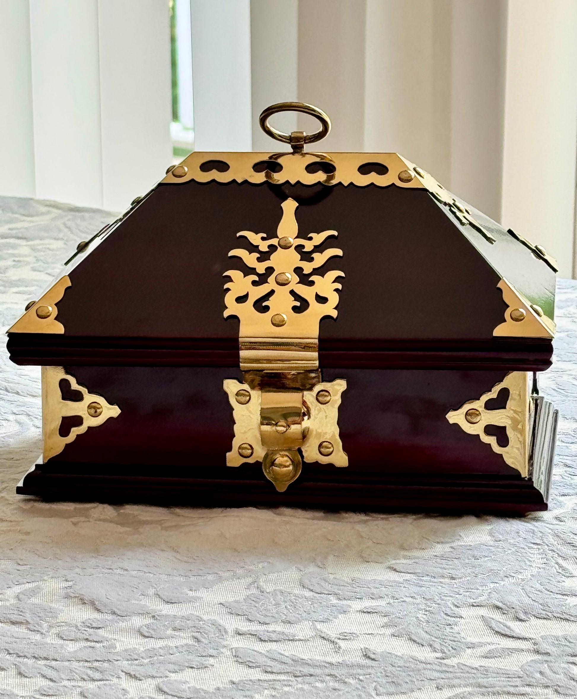 Rosewood  Netturpeti jewelry box with gold accents on a textured surface