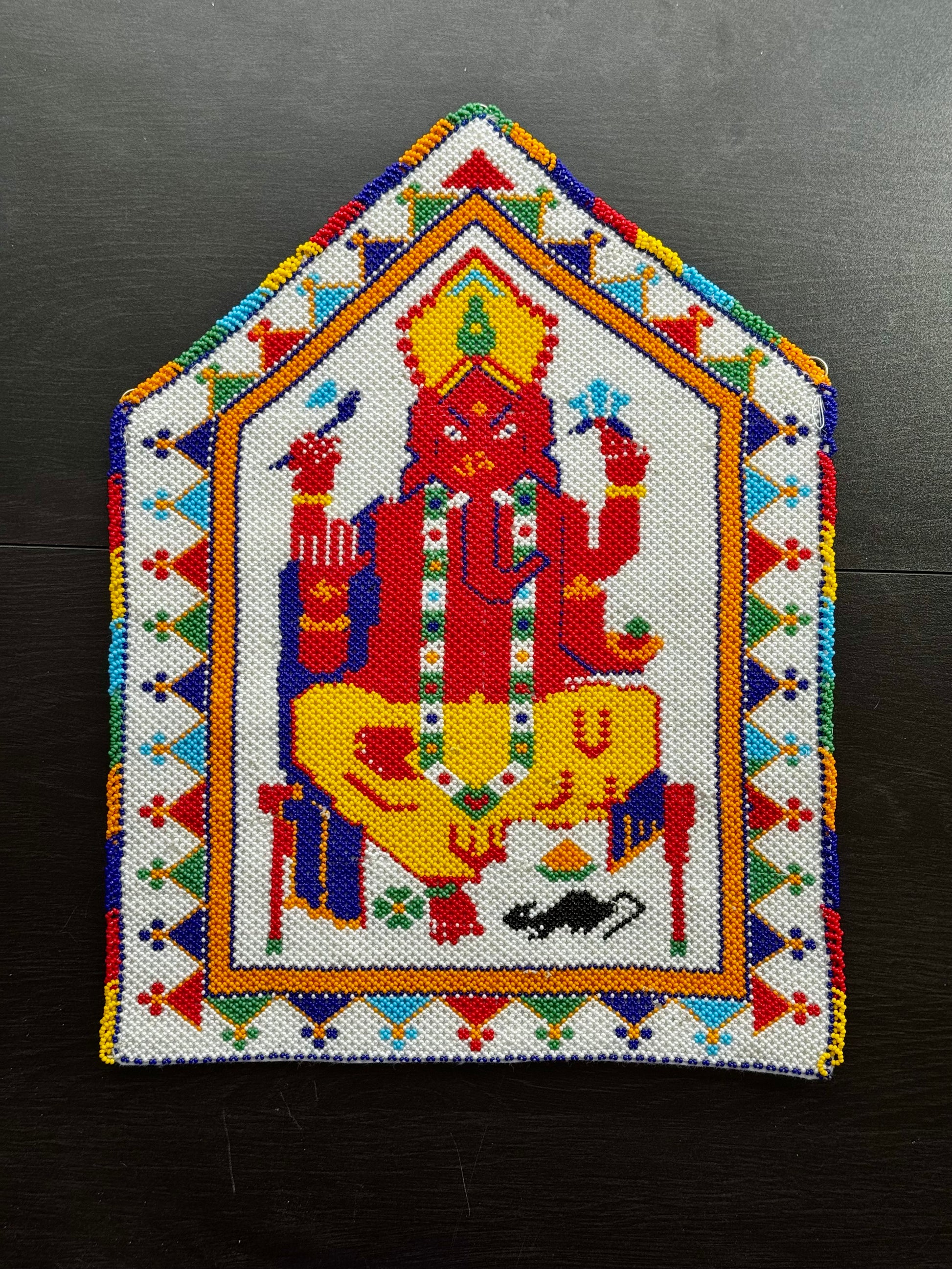 Colorful Motikaam design of a deity on a geometric patterned background