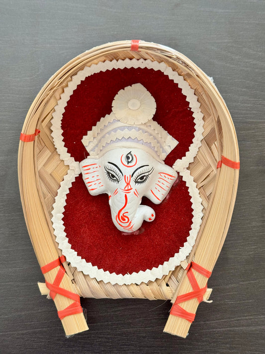 Decorative item with a Ganesha white figure on a red background, placed inside a woven frame.