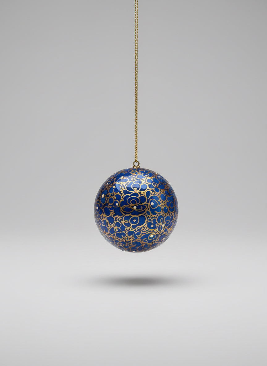 Decorative blue ball with gold patterns hanging on a gray background