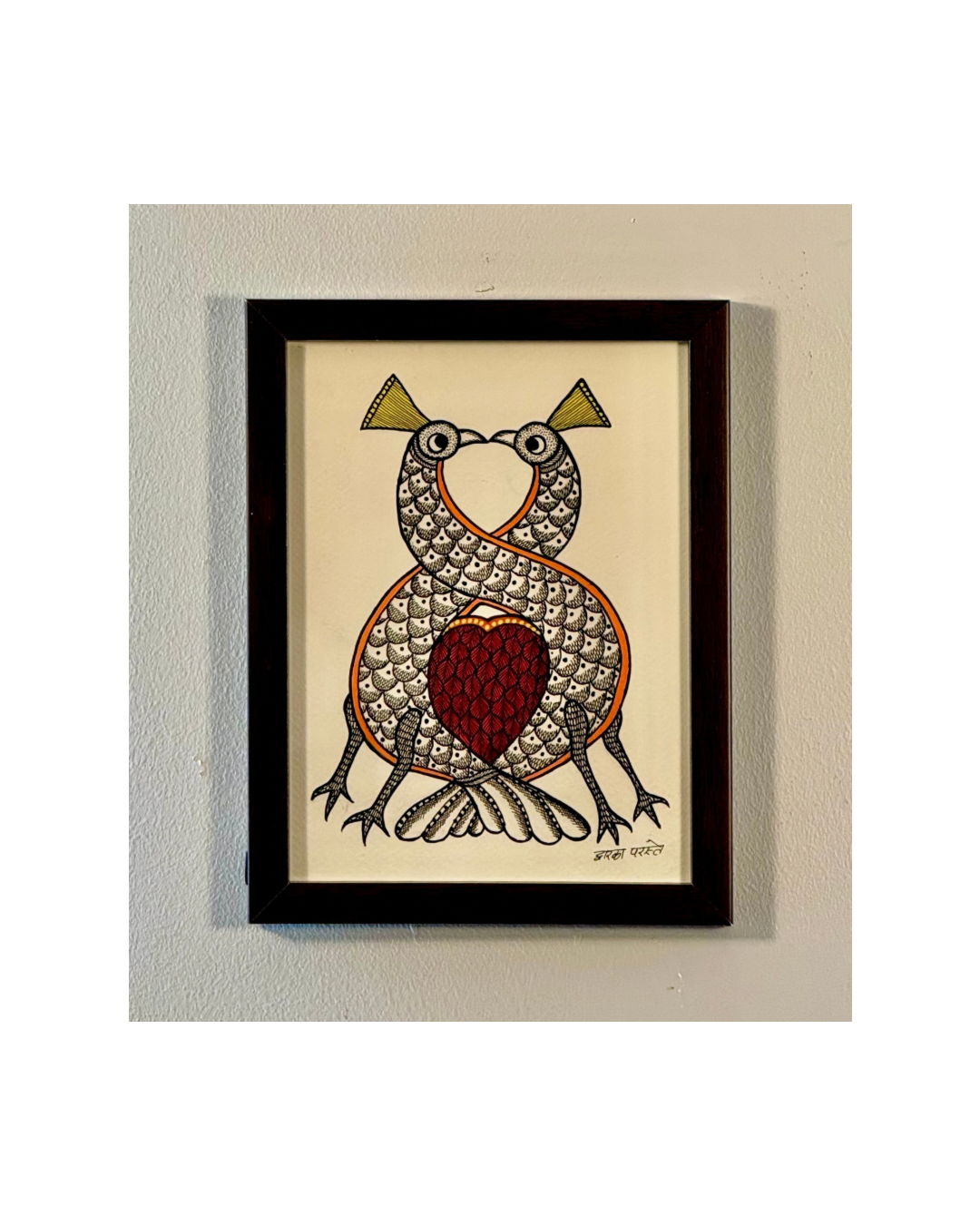 Framed Gond artwork of two peahens with a red heart on a beige background