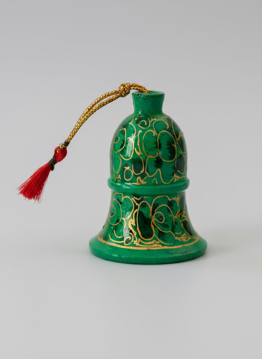 Decorative green bell with gold patterns on a wooden surface