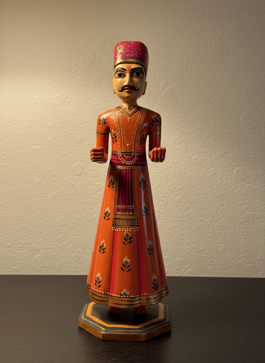 Traditional wood figurine in ornate clothing on a reflective surface with a blurred outdoor background