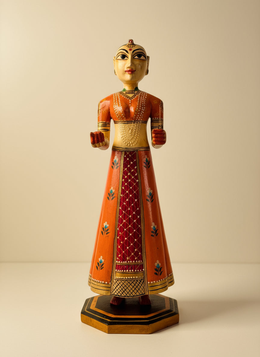 Traditional wood figurine in an orange and red outfit on a striped surface