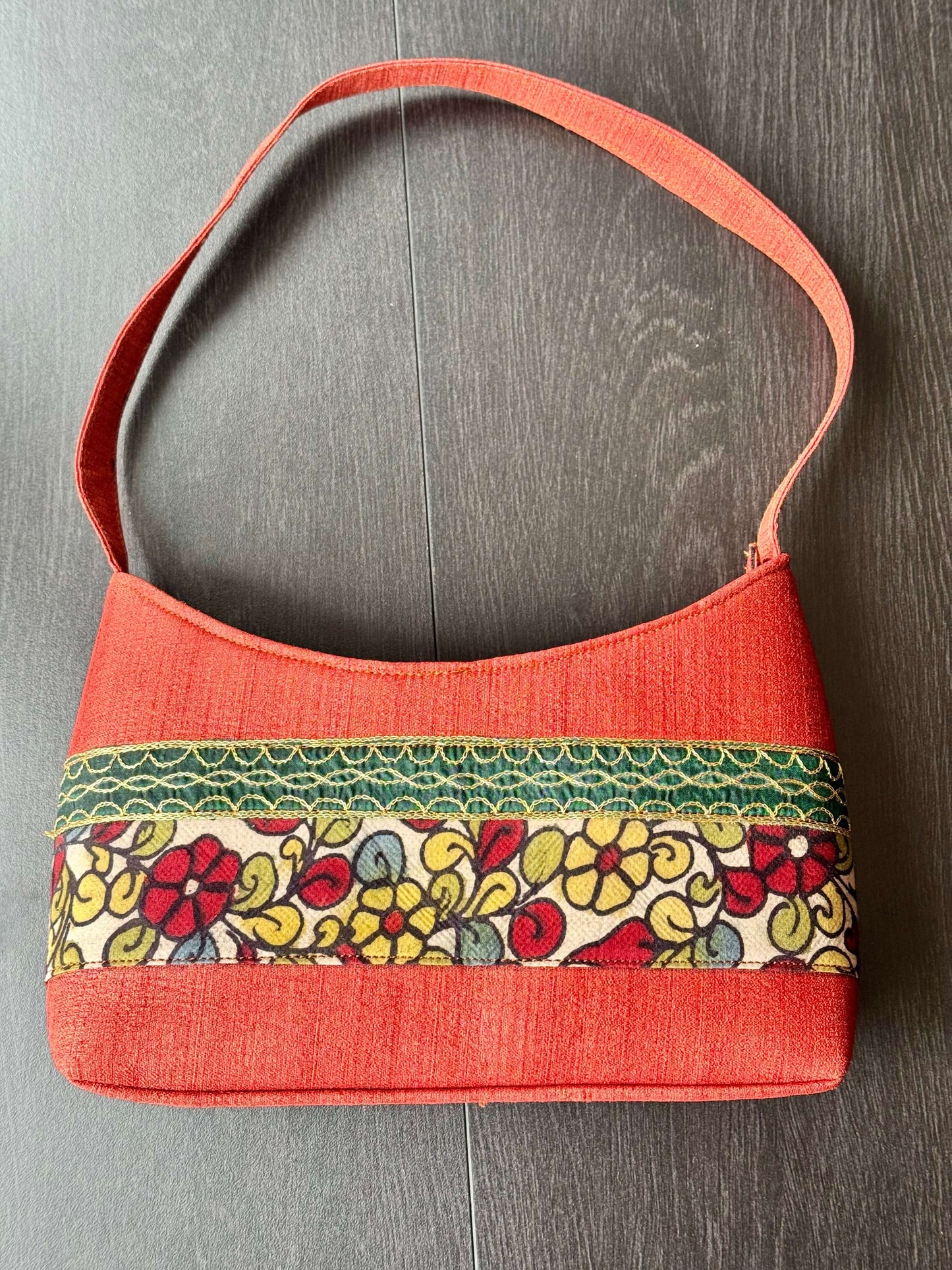 Handbag with floral patterned band on a wooden surface