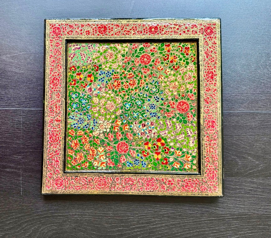 Kashmiri paper Mache wall piece/decorative tray with floral pattern on a wooden surface