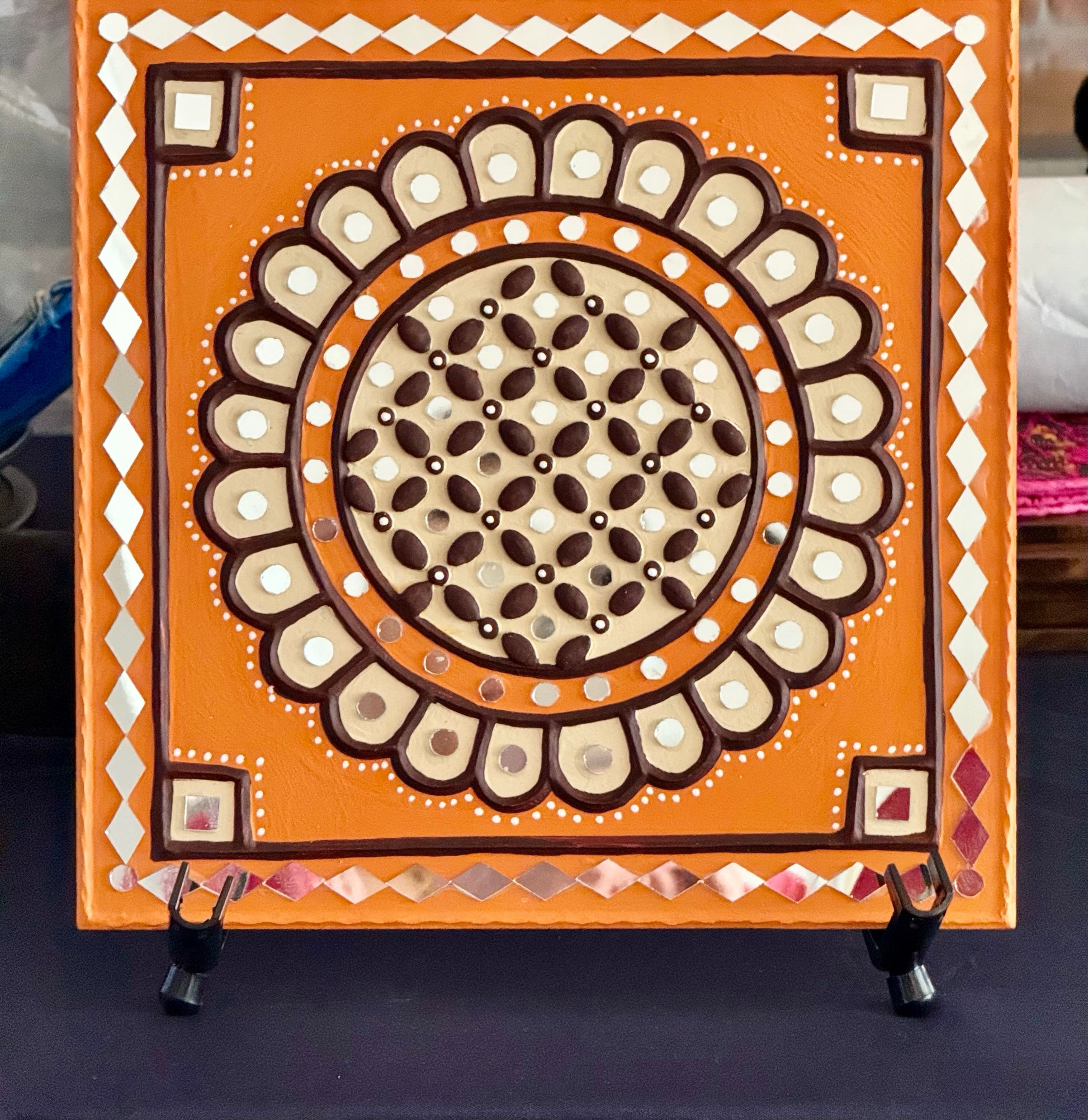 Decorative square panel with intricate circular design on an orange background