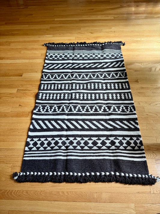 Black and white patterned Kharad rug on a wooden floor