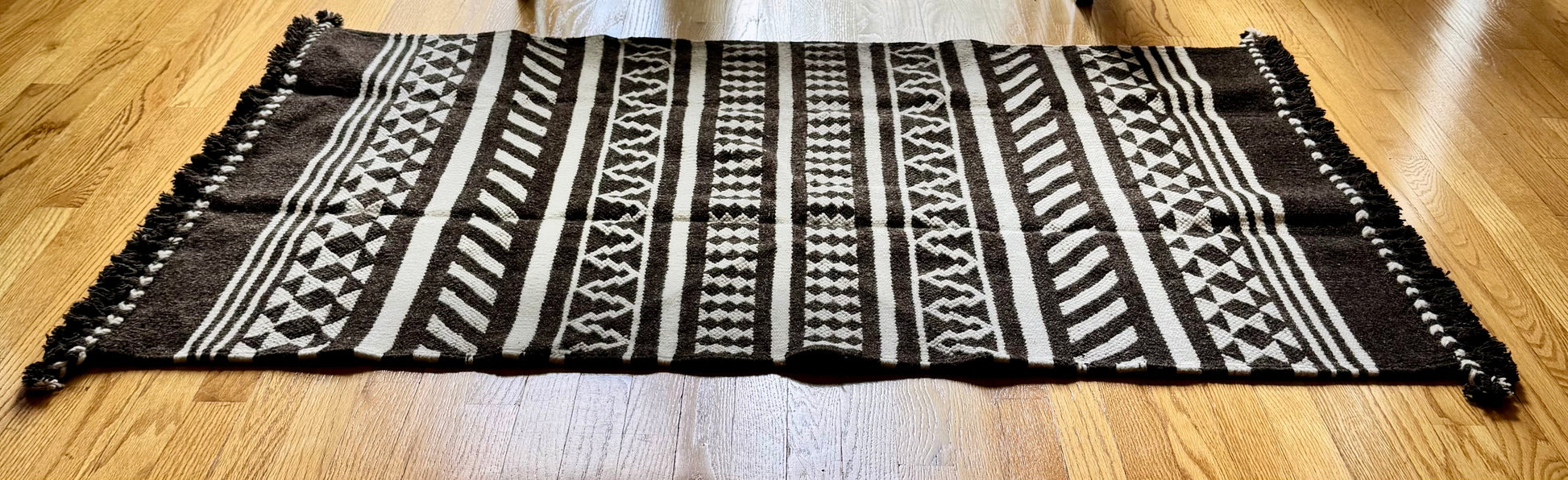 Black and white patterned Kharad rug on a wooden floor