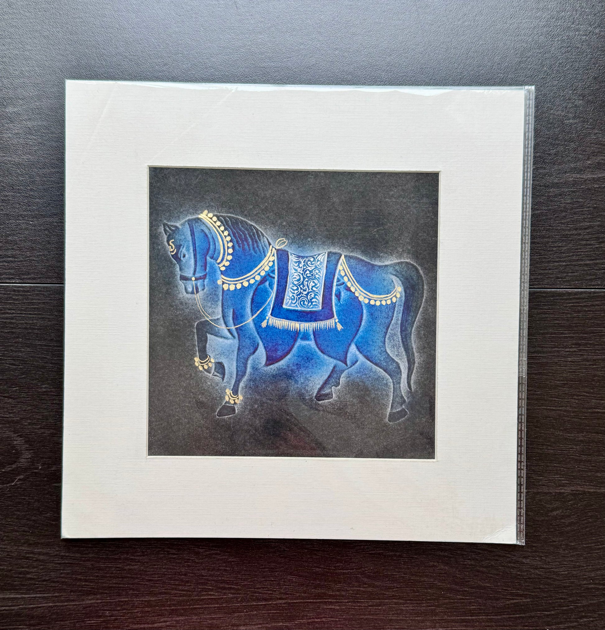Decorative nail drawn artwork of a blue horse with intricate details on a dark background, framed in white.