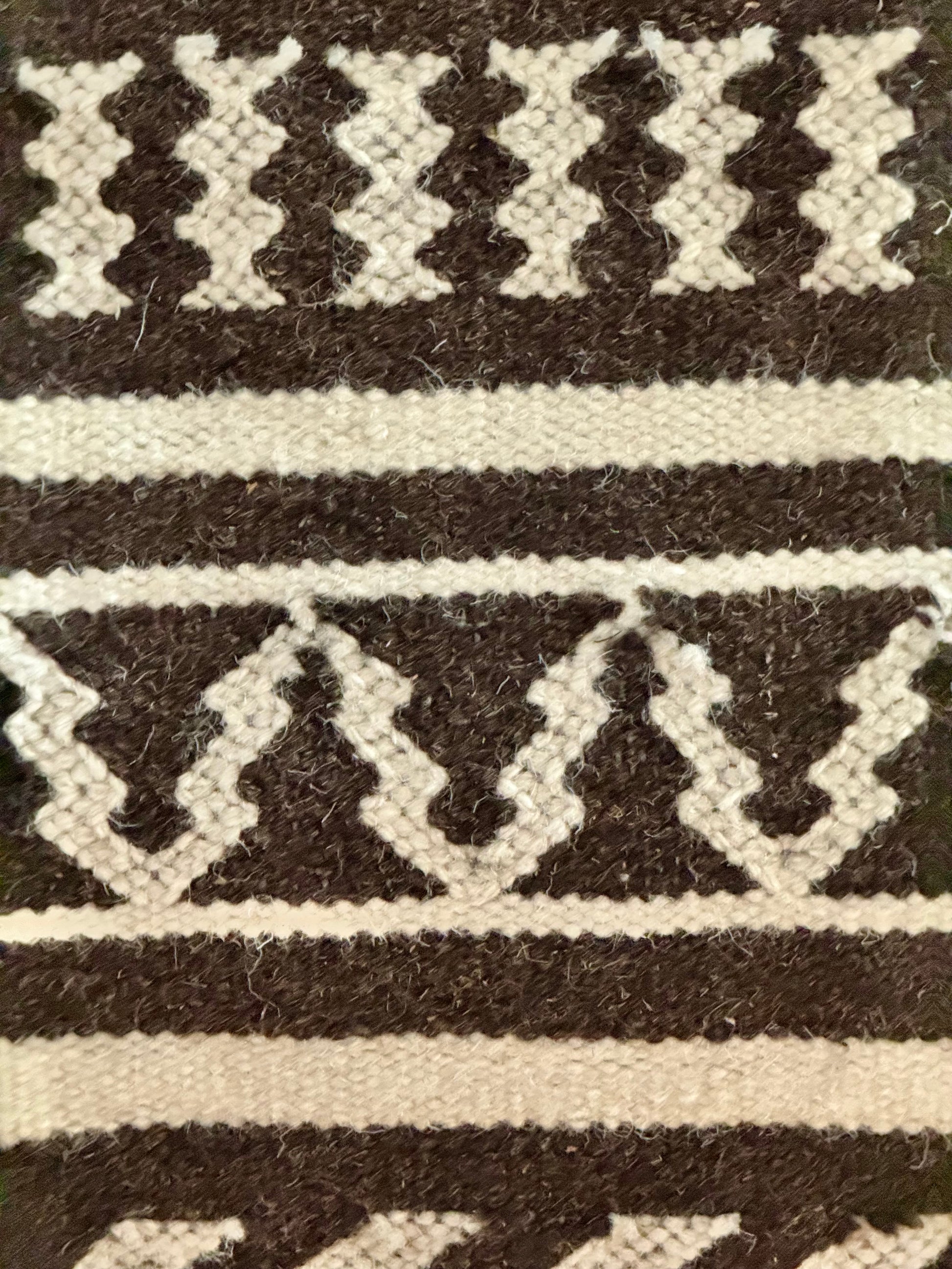 Close-up of a woven pattern Kutchi Kharad rug with black and white stripes on a textured background