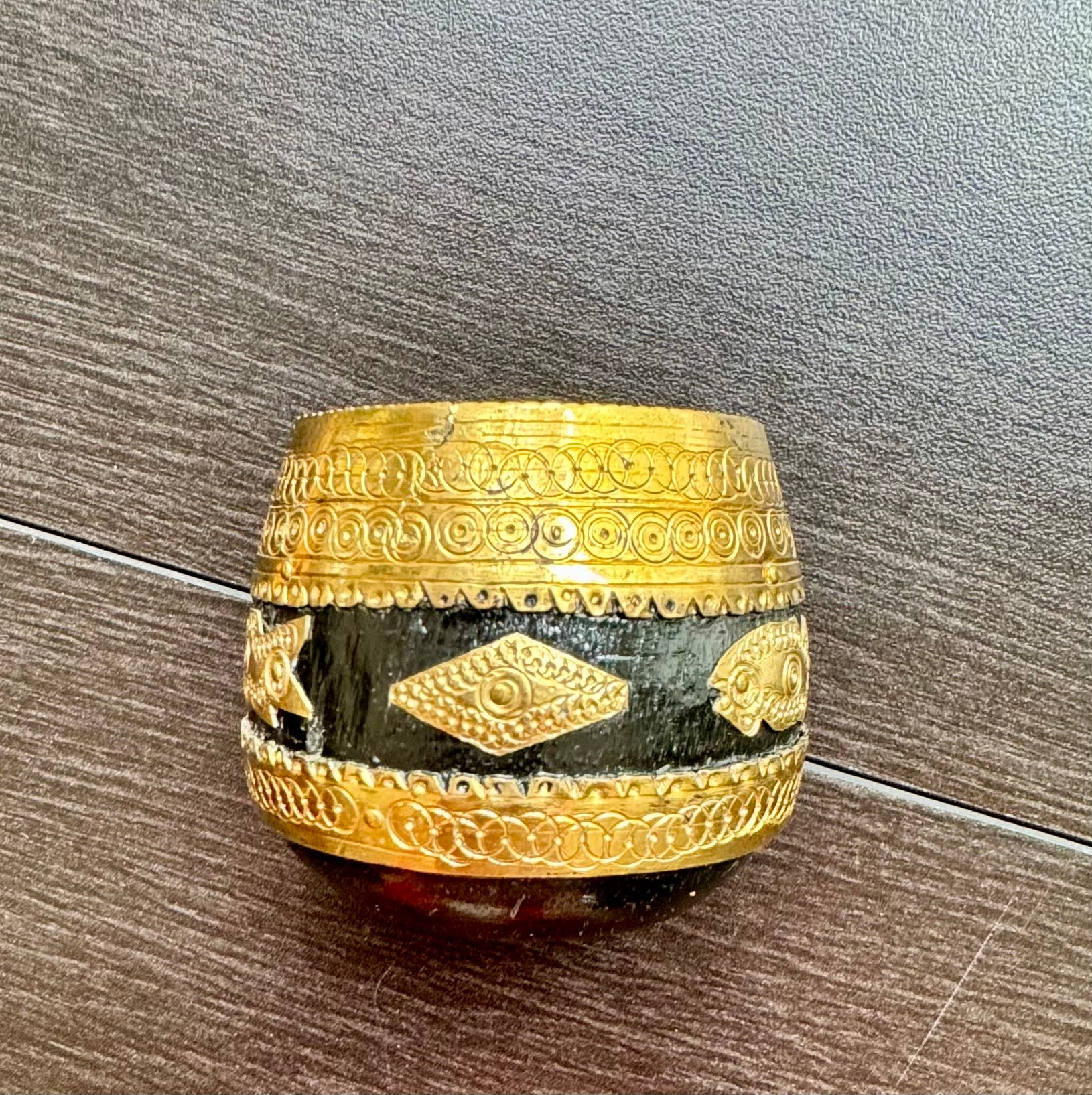Decorative Sherpai bowl with gold band and black stone on a wooden surface