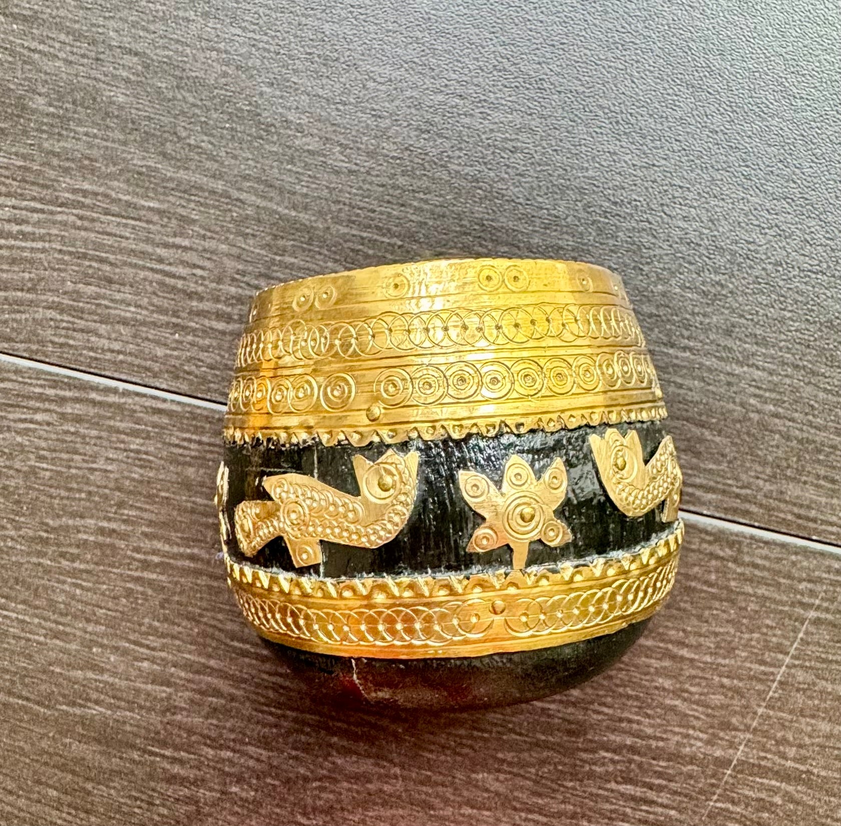 Decorative black and gold Sherpai bowl with intricate patterns on a wooden surface