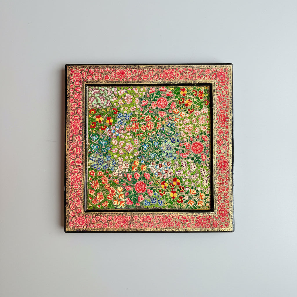 Decorative floral patterned Kashmiri Paper Mache decorative tray/wall piece in a decorative frame on a dark surface.