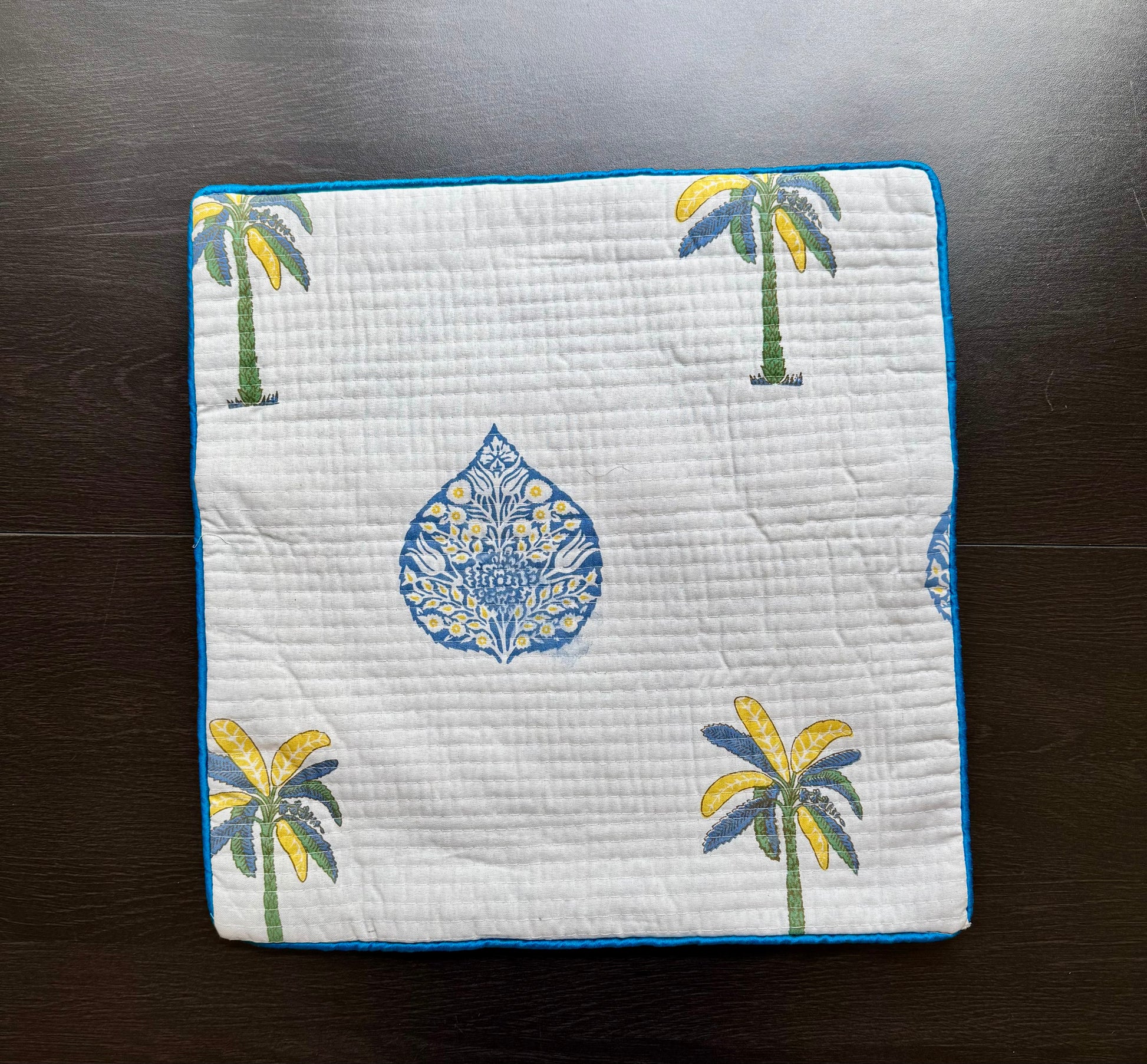 Quilted hand block printed cushion cover with palm tree and floral pattern on a dark surface