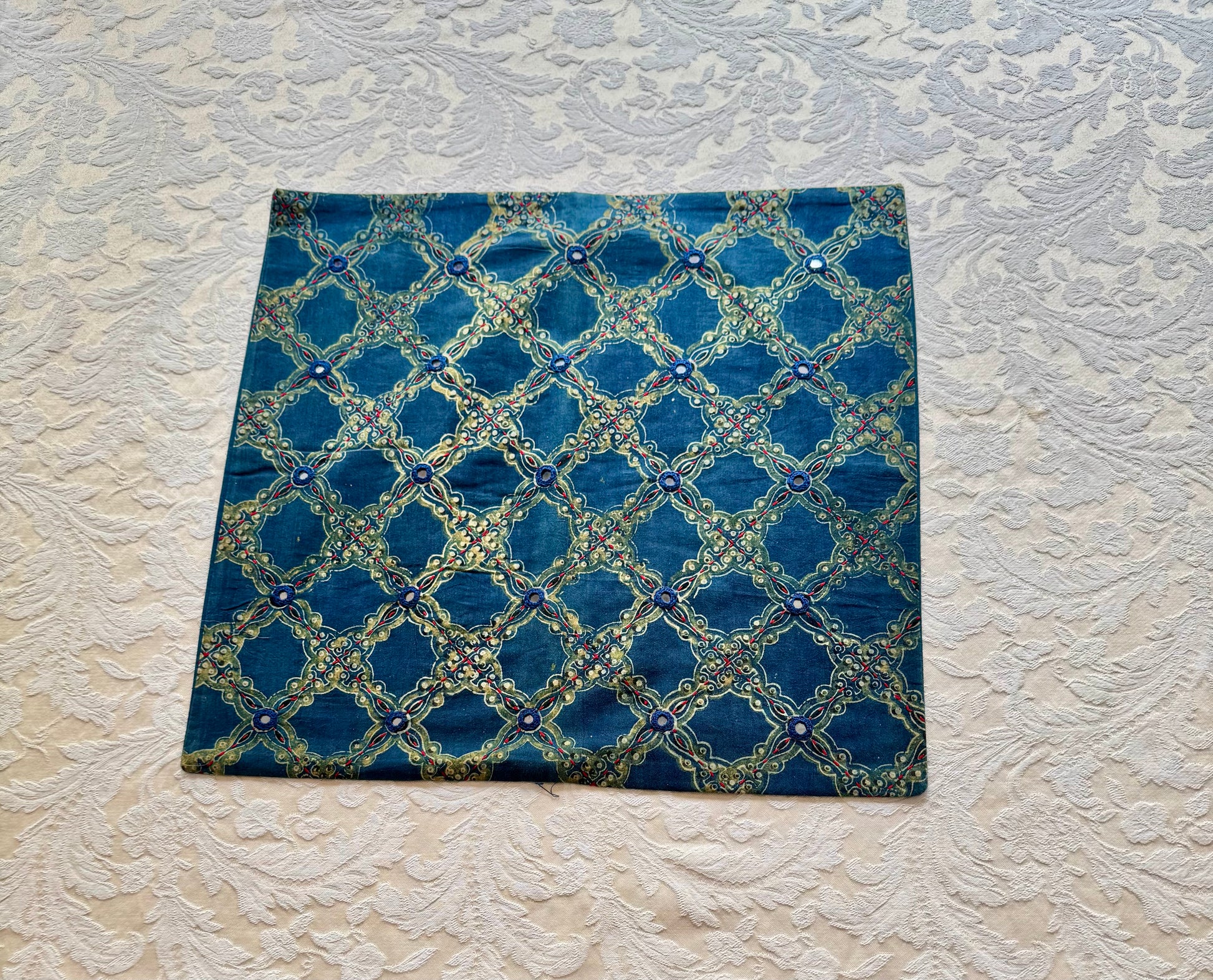 Blue fabric pillow in Ajrakh hand block print with geometric pattern on a textured white background