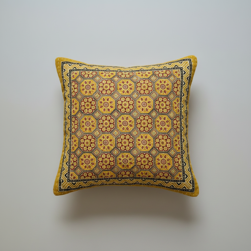 Decorative pillow with yellow and brown Ajrakh hand block print pattern on a gray background