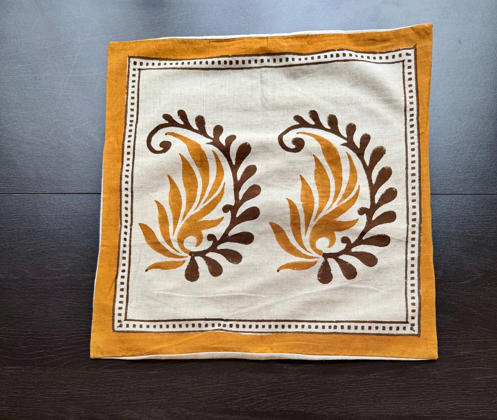 Hand block printed cushion cover with floral patterns on a wooden surface