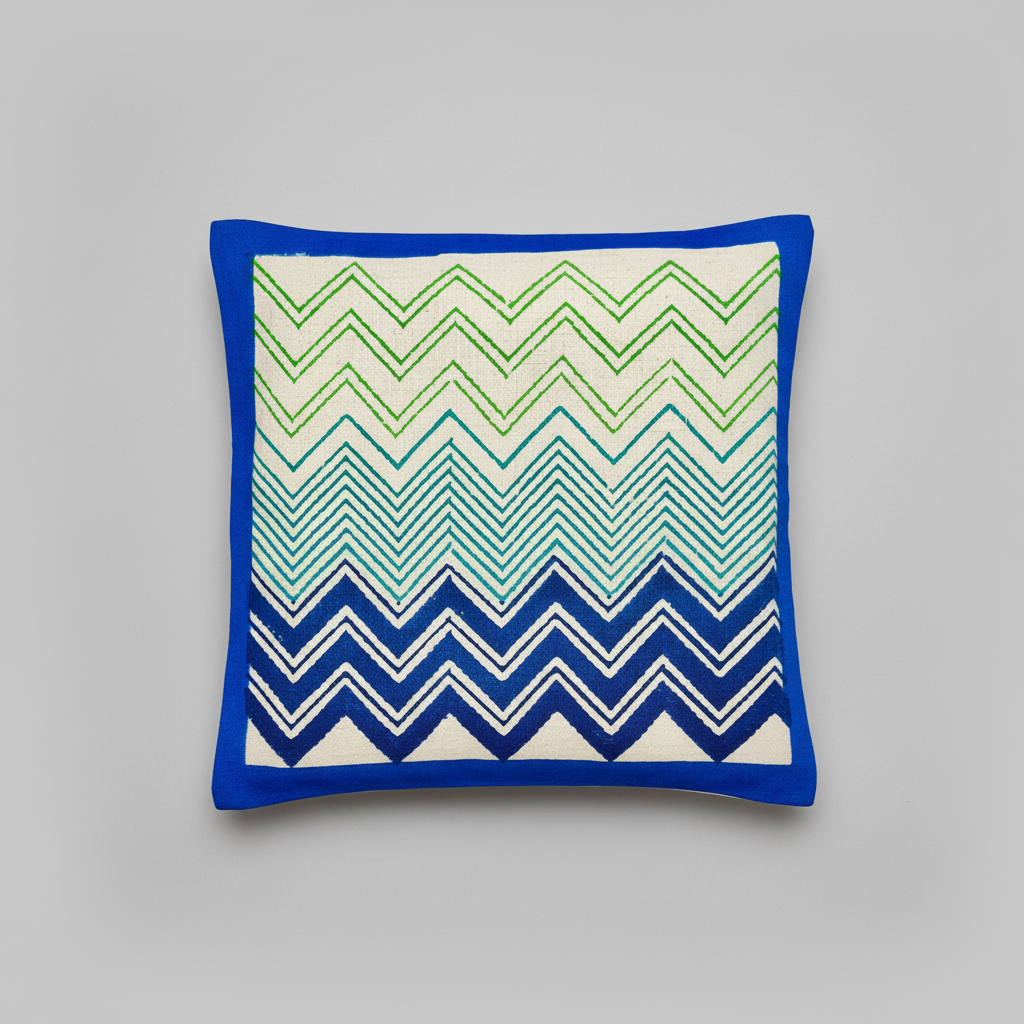 Hand block print cushion cover with blue, green, and white zigzag pattern on a wooden surface