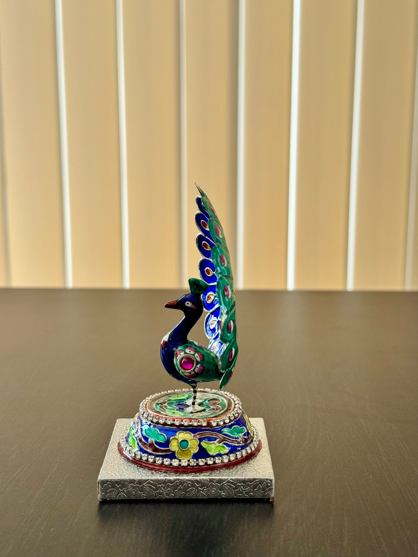 One side of Gulabi Meenakari silver  peacock feather sculpture on a stand with a neutral background