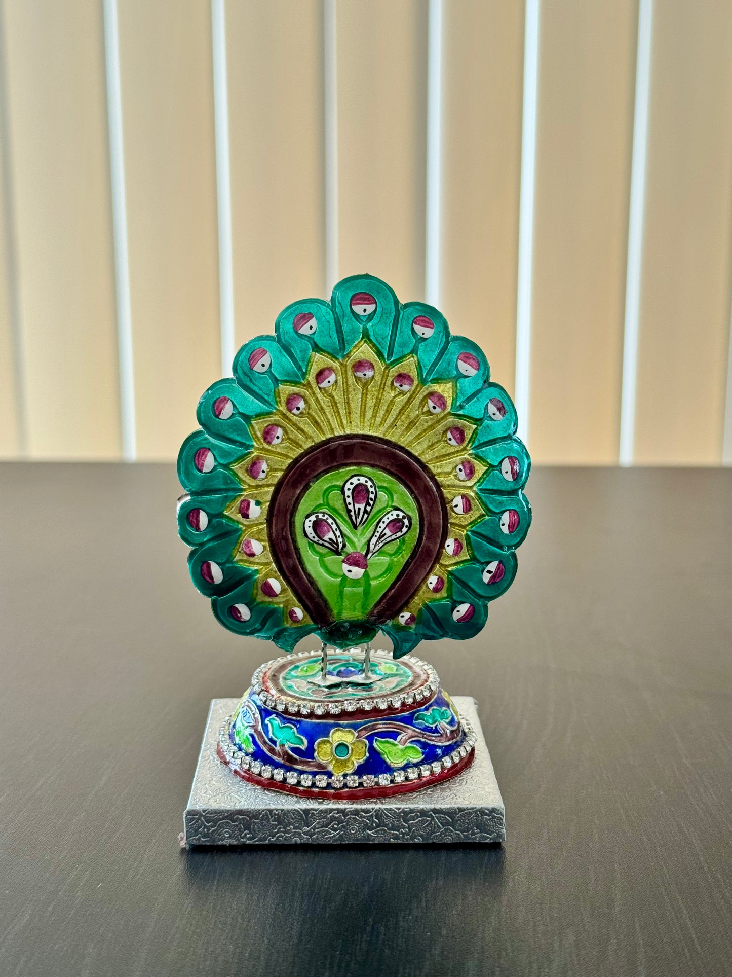 Back of Gulabi Meenakari silver  peacock feather ornament on a stand with a neutral background
