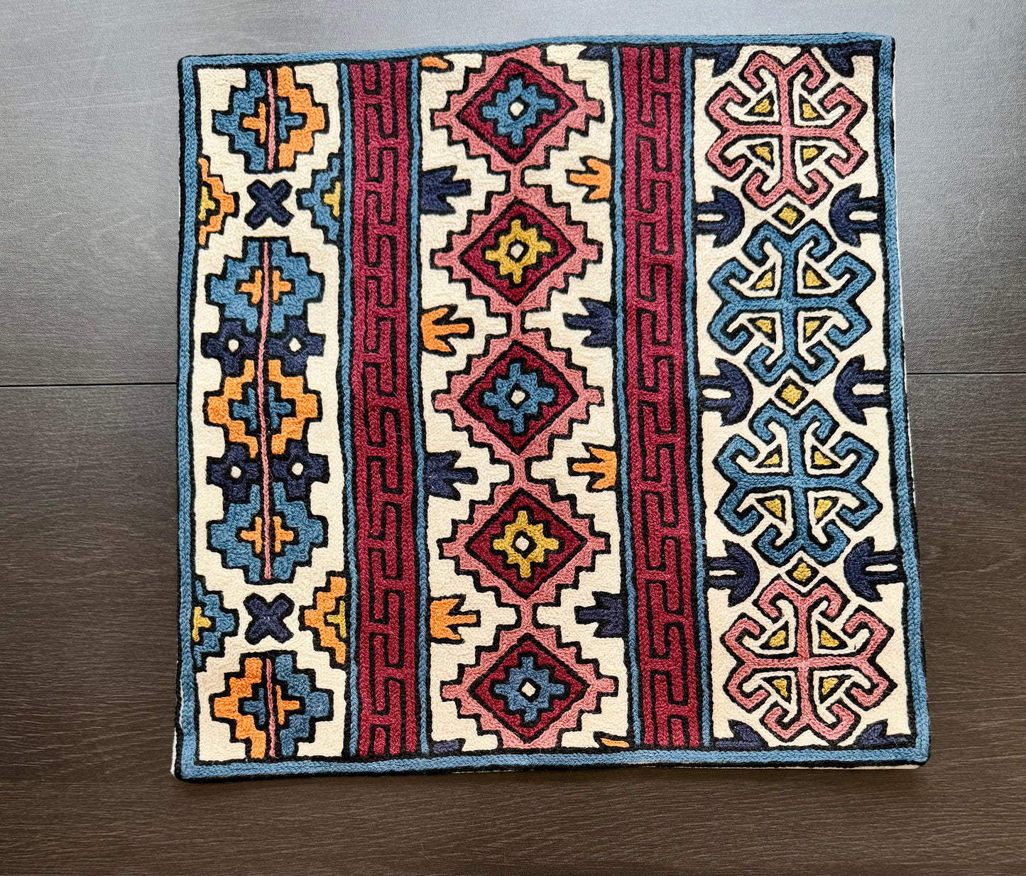 Decorative cushion cover with Kashmiri embroidery geometric patterns on a wooden floor