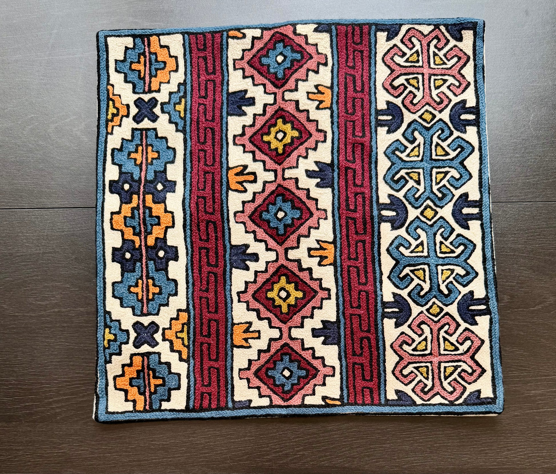 Decorative cushion cover with Kashmiri embroidery geometric patterns on a wooden floor